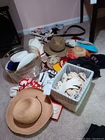 Wide view of the collection showing variety of hats, gloves in striped box, several belts on table