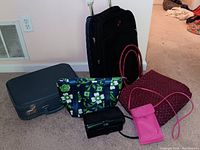 Photo of entire lot showing black rolling suitcase, blue vintage suitcase, floral makeup bag, black Mary Kay clutch wallet, pink woven tote, and pink Mary Kay crossbody wallet bag.