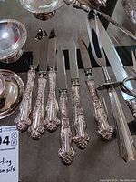 Ornate-handled fruit knives (6) and carving utensils at edge; partial view of bowls at top
