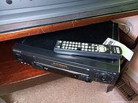Sony SLV-N60 VHS player recorder unit with remote control on top, showing front view with buttons and cassette slot.