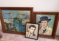 Three framed prints on carpeted floor: Leonard Bernstein autograph portrait in center front, painting of man in hat on right, colorful bridge scene on left.