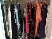 Photo of hanging vintage women's clothing including jackets, dresses and tops in various colors and patterns.