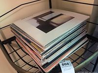 Stack of vinyl records albums on a black metal shelf, visible are album edges and sleeves.