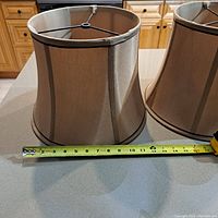 Two lamp shades placed on a kitchen counter with measuring tape at base showing approximately 13 inch diameter for the larger shade.