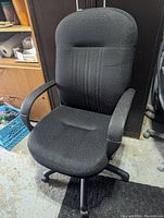 Front view of the black office chair showing padded seat, backrest, and armrests.