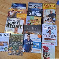 Twelve books laid out on floor with visible titles about cooking, diet, health, renovation, and trauma life support.