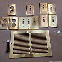 Brass electrical outlet and switch plates along with a brass vent cover and a mounting spacer.
