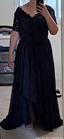 Full length photo showing navy blue chiffon formal dress with lace bodice and flowing layered skirt worn by person.