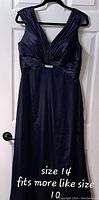 Front view of navy blue formal gown showing V-neck and pleated waist with rhinestone brooch