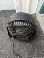 Rear view of Honeywell fan showing ventilation fins, power cord, and power switch, placed on concrete ground.