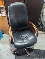 Front view of the black leather office chair showing seat, backrest, and wooden armrests.