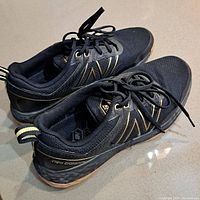 Side and top angle showing pair of black and gold New Balance golf shoes size 11.5