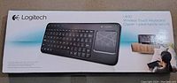 Photo of the Logitech K400 Wireless Touch Keyboard in original packaging showing the keyboard and touchpad design, with product branding and model number.