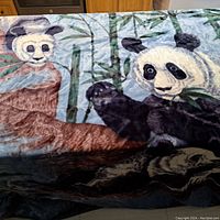 Photo showing detailed plush panda faces and surrounding bamboo design on the blanket.