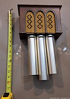 Retro doorbell with three silver chimes and decorative top next to a measuring tape showing approximately 13 inches in height.