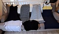 Six women's summer clothing items including three dresses on right, a striped skirt, black sleeveless dress, and Calvin Klein T-shirt on floor