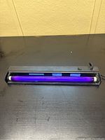Black light UV lamp powered on showing violet light emission from the fluorescent bulb.
