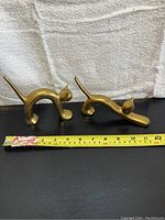 Two brass cat bookends displayed side by side with measuring tape showing about 6 inches in length.