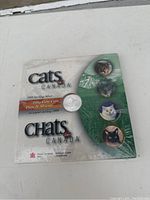 Photo of the front cover of the Cats of Canada 1999 sterling silver fifty cent coin package showing images of cats and the coin positioned in the center.