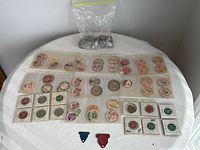 Top view of vintage milk bottle tops collection spread on table, showing various brands and colors mainly beige with red and green print
