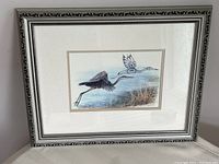 Full view of the framed art showing the heron flying over water with the frame and matting visible.