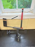 The full wooden weather vane positioned on a flat surface showing the missing east directional marker and the figure on top.