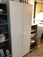 Front view of a 6 foot tall white cabinet with two doors and vertical handles, showing surface dirt and wear.