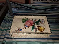Rectangular ceramic tray with basketweave textured edges and hand-painted floral design in pink, yellow, green, blue, and brown colors on cream ceramic.