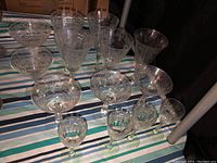 Set of crystal glasses of varying sizes on striped fabric, showing etched designs and clear glass