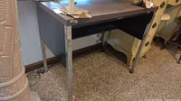 Metal office desk angled view showing worn black top surface and metal legs