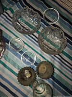 Top view of glass bowls, coasters, and candle holders on striped fabric.