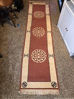 Full view of hallway rug runner on carpeted floor, showing its length, color, pattern, and frayed fringe ends.