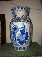Front view showing blue floral and bird motifs on the vase with decorative handles on the neck