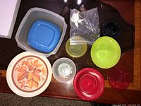 Photo showing various plastic and glass bowls, storage containers with lids, and a decorative plate with autumn leaf design