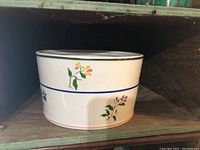 White ceramic crock pot with green and blue painted bands and floral motifs.