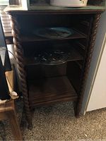 Wooden shelf showing twisted spiral column design and open shelves with items placed for scale only.