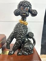 Front view of the black ceramic French poodle dog figurine showcasing the detailed curly fur texture and gold collar.