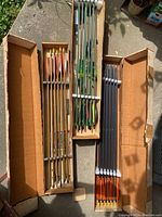 Three boxes of custom arrows with different shaft colors and fletching, showing arrowheads and feathering.