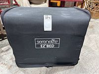 Front view of the black carry case with 'SereneLife EZ Bed' branding and auction tag attached.