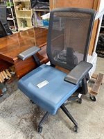 Front view of the Hayworth office chair showing blue cushioned seat, black mesh backrest, and adjustable black armrests.
