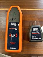 Front view of Klein Tools ET300 receiver with orange casing and transmitter unit on wooden surface.