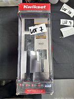 Front view of Kwikset lock set in plastic box showing handle and keypad, labeled Lot 7.