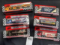 Top-down photo showing all seven new in box Matchbox transporter truck models with various vehicle and brand decals.