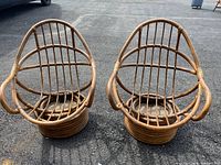 Pair of mid century boho style bamboo rocker chairs with no cushions on blacktop surface.