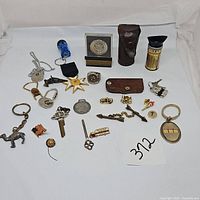 Full view of entire lot with various keychains, rings, medallions, cases, and small gadgets on white background