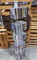 Full tall metal CD storage tower holding approximately 120 CDs across five shelves, rack showing slight wear but solid construction.