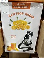 Box front showing Eurolux Citrus Press Cast Iron Juicer includes stainless steel cup, graphics of citrus slices and fresh orange juice glass.