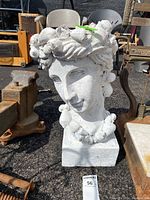 Front view of the white outdoor head planter with shell decorations, showing facial features and necklace detail.