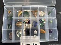 Top view of plastic organizer tray containing an assortment of polished stones of various colors and shapes including green, blue, striped, and iridescent pieces.