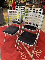 Four Samsonite metal folding chairs positioned on a red carpet.